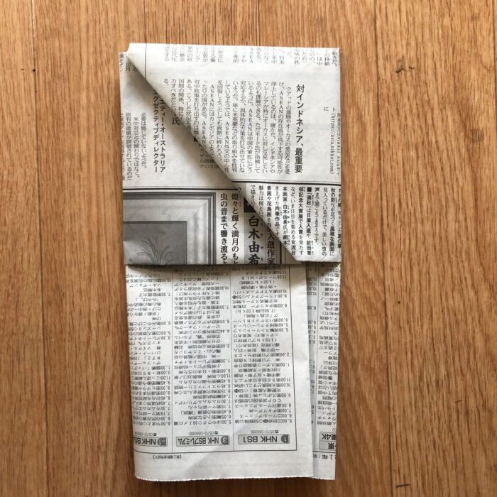 7.6で差し込んだ後に一番上にある新聞紙の部分の端を、三角に折り込む２