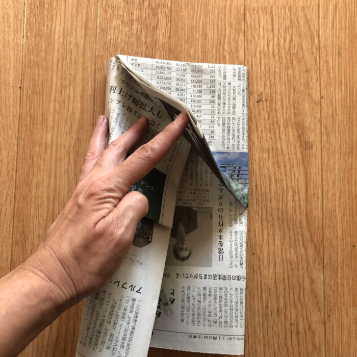 6.折り込んだ片側の新聞紙を、もう片側の新聞紙の中に挟み込む